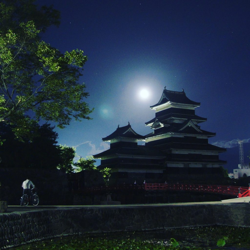 Matsumoto Castle, the crow castle in a full moon night with a biker admiring the view